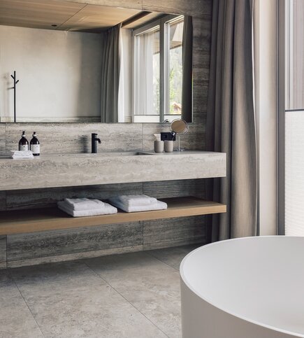 Luxury bathroom with bathtub in the penthouse A modern bathroom with a freestanding bathtub, stone vanity, and folded towels by the window.