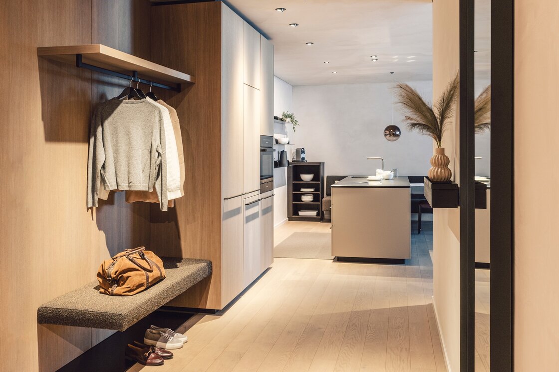 Apartment mit Garderobe und Küche in Fiss Der Eingangsbereich eines Apartments zeigt Garderobe, Bank, Küche und Essbereich in warmen Holztönen.