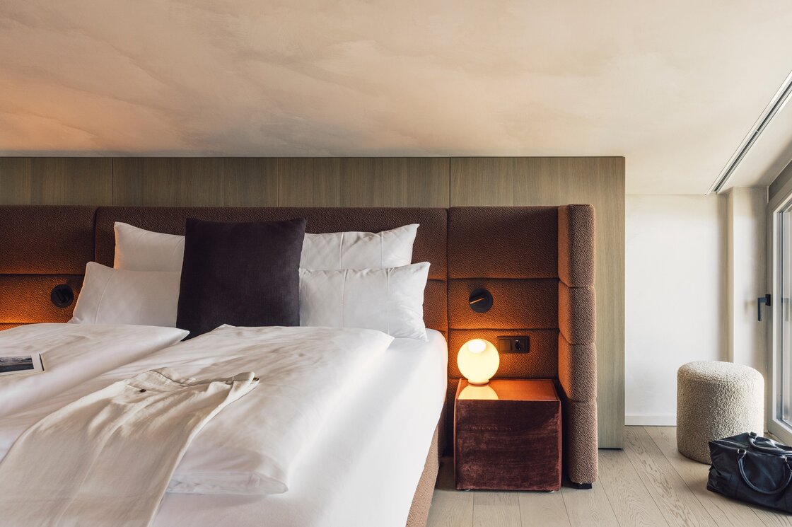 Schlafzimmer im Luxury Penthouse 2 in Fiss Ein modernes Schlafzimmer mit Doppelbett, gepolstertem Kopfteil und Nachttischlampe neben großen Fenstern.