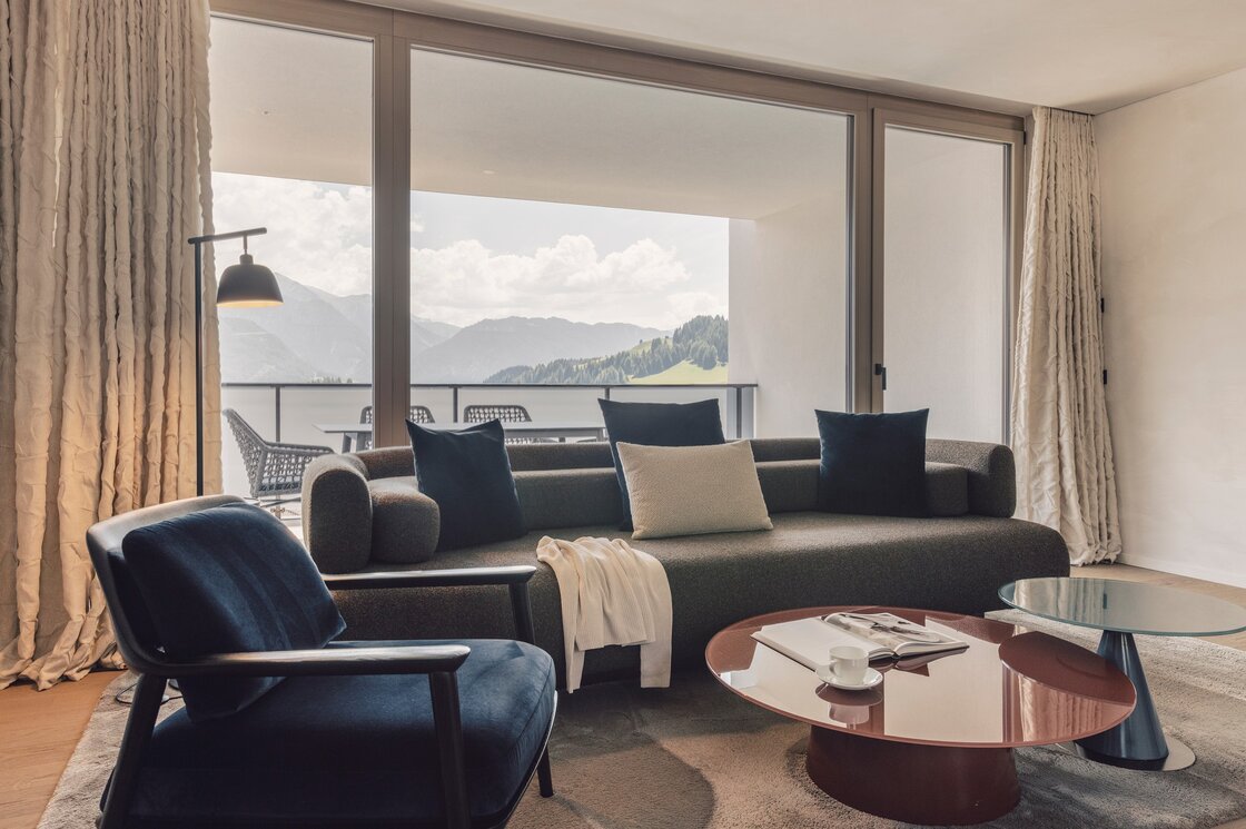 Apartment mit Balkon und Bergblick in Fiss Wohnbereich eines Apartments mit Sofa, Sessel und großem Fenster zum Balkon mit Bergblick.