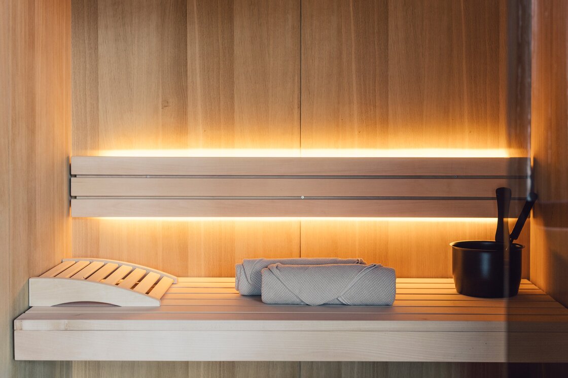 Private Sauna im Penthouse in Fiss Holzsauna mit Liegefläche, Handtüchern und Aufgusseimer in warmem Licht.