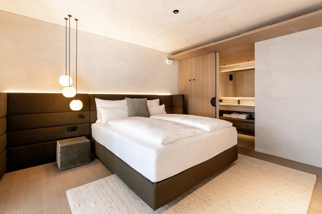 Schlafzimmer im Luxury Apartment 4 in Fiss Ein modern eingerichtetes Schlafzimmer mit Doppelbett, warmen Pendelleuchten und Blick ins angrenzende Bad.