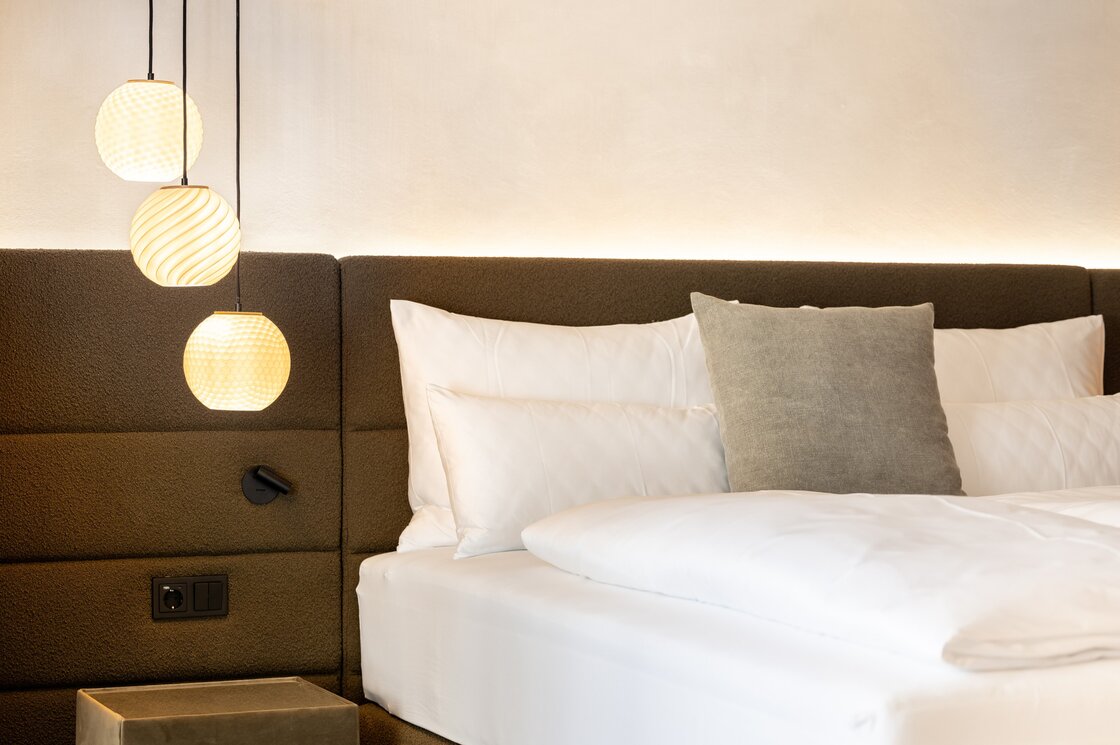Luxus-Apartment Schlafzimmer in Fiss Ein modernes Schlafzimmer mit Doppelbett, gepolstertem Kopfteil und drei Hängelampen.