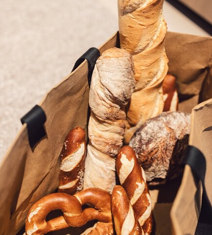 Bread in a Paper Bag Different breads and pretzels are placed in a paper bag.