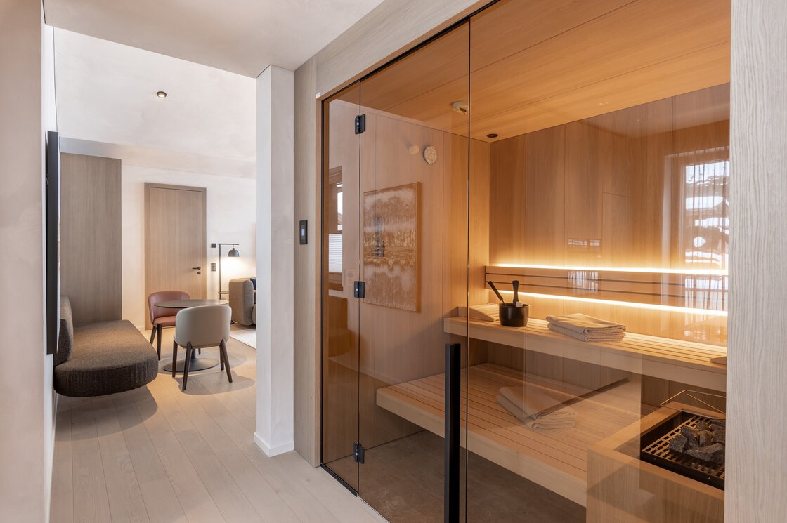 Penthouse mit privater Sauna in Fiss Ein moderner Wohnbereich mit Glasfront zur privaten Sauna und Sitzmöbeln im Penthouse.