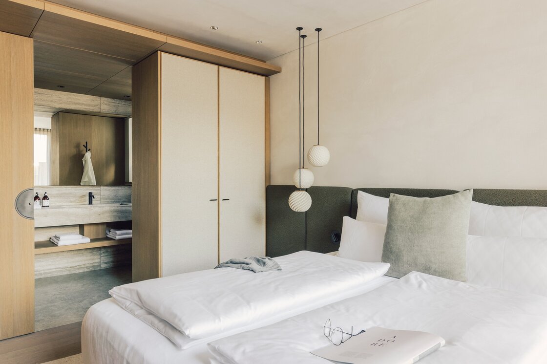 Schlafzimmer im Apartment mit Ensuite-Bad Ein modernes Schlafzimmer im Apartment mit Doppelbett, Hängeleuchten und offenem Badbereich.