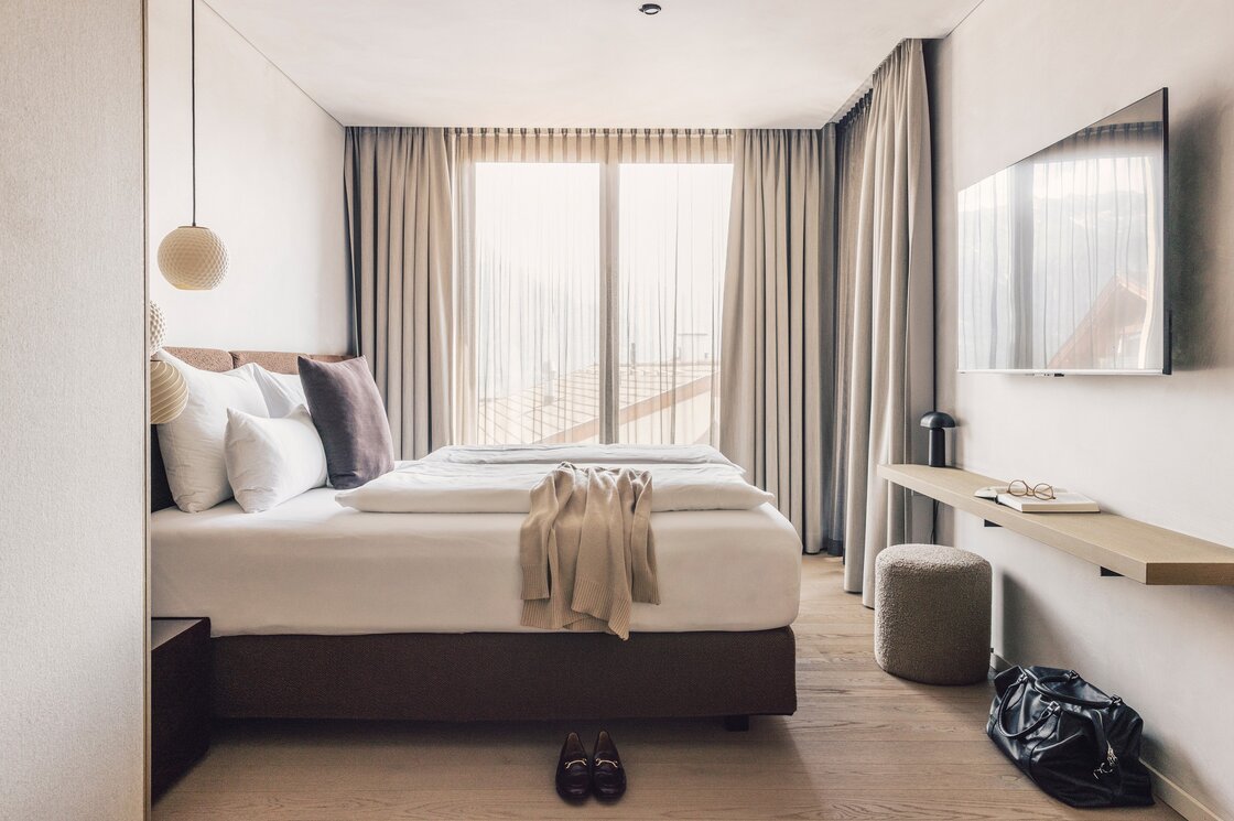 Schlafzimmer im Luxury Apartment 2 in Fiss Ein helles Schlafzimmer mit Doppelbett, großen Vorhängen und Schreibtisch in einem Apartment in Fiss.