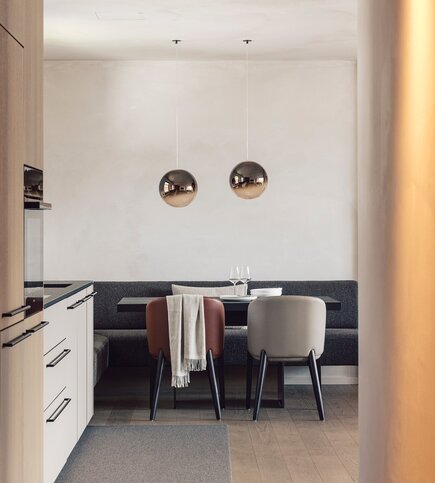 Apartment mit Essbereich und Küche in Fiss Ein moderner Essbereich mit Tisch, zwei Stühlen und Küchenzeile in einem Apartment.