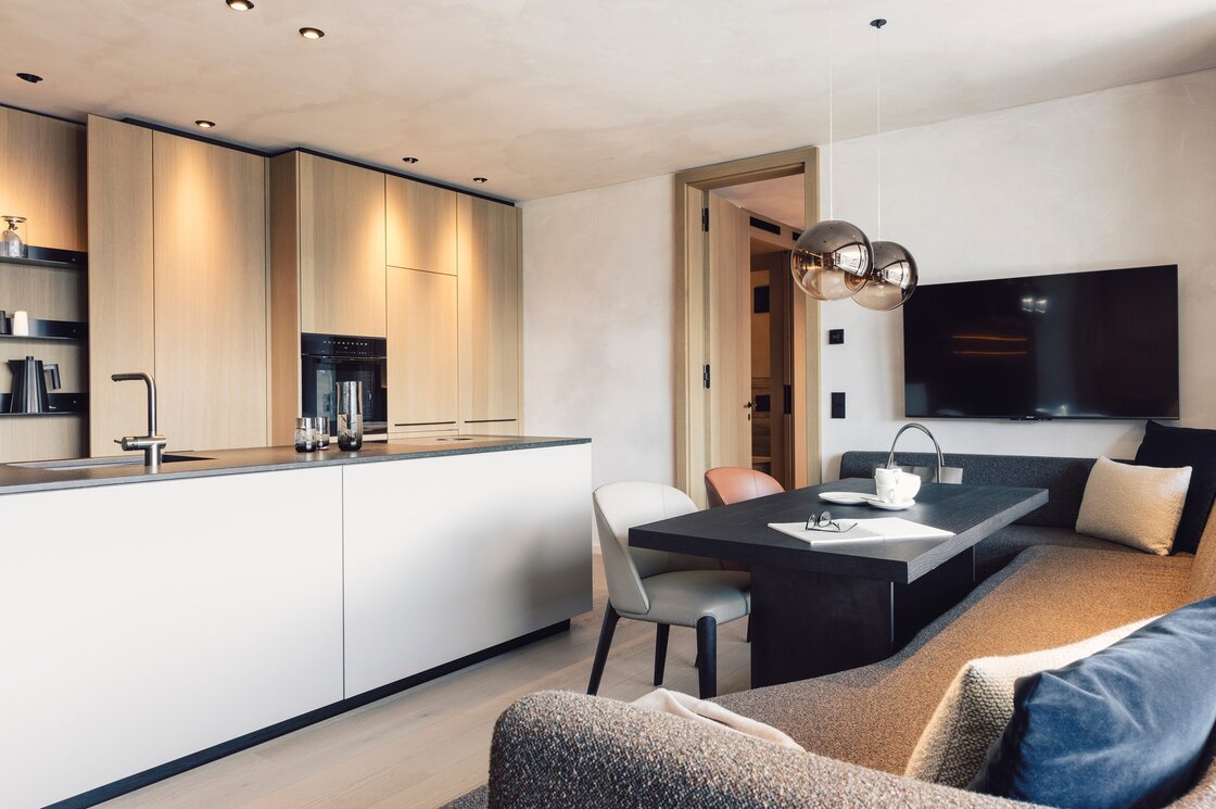 Apartment mit Küche und Wohnbereich in Fiss Der offene Küchen- und Wohnbereich zeigt eine moderne Einrichtung mit Esstisch, Sofa und großer Kochinsel.