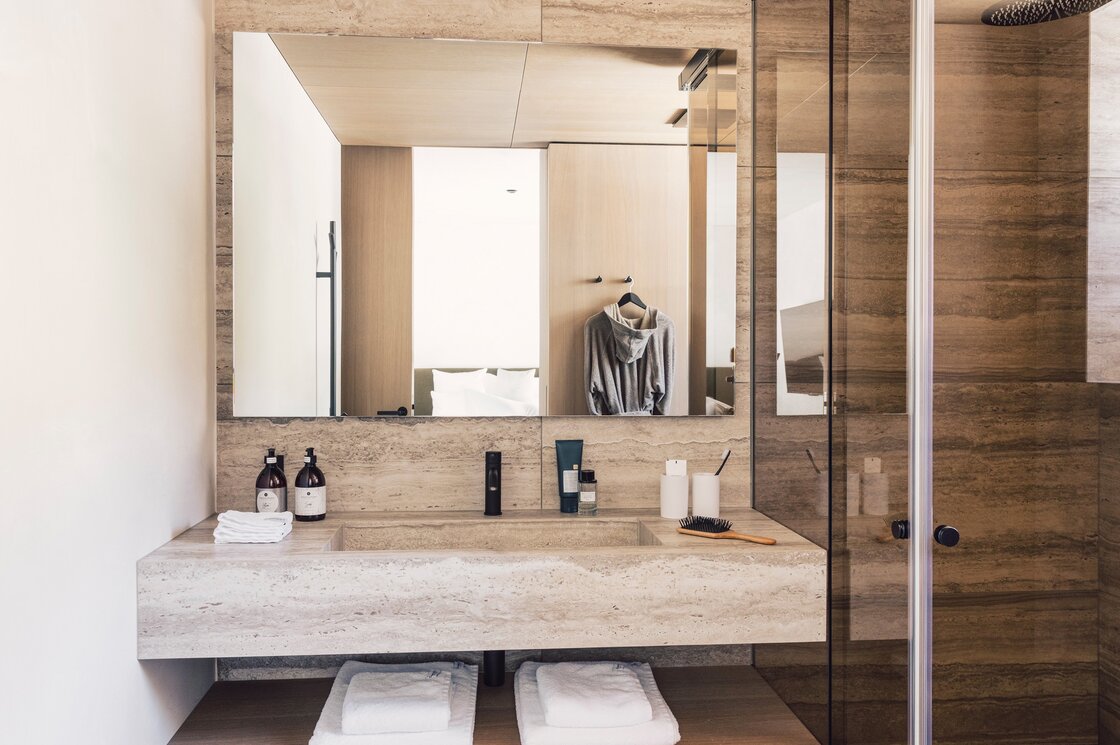 Badezimmer im Luxury Apartment 6 in Fiss Modernes Badezimmer mit Doppelwaschbecken, Spiegel, Dusche und Pflegeprodukten im Apartment.
