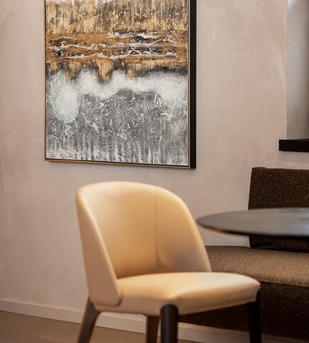 Wohnbereich mit Kunstwerk im Luxury Penthouse 3 Ein moderner Wohnbereich mit Stuhl, Tisch und abstraktem Wandbild.