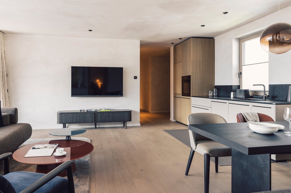 Luxury Apartment 6 in Fiss mit Wohnküche Wohnbereich und Küchenzeile in einem modernen Apartment mit Esstisch, Sofa und TV.