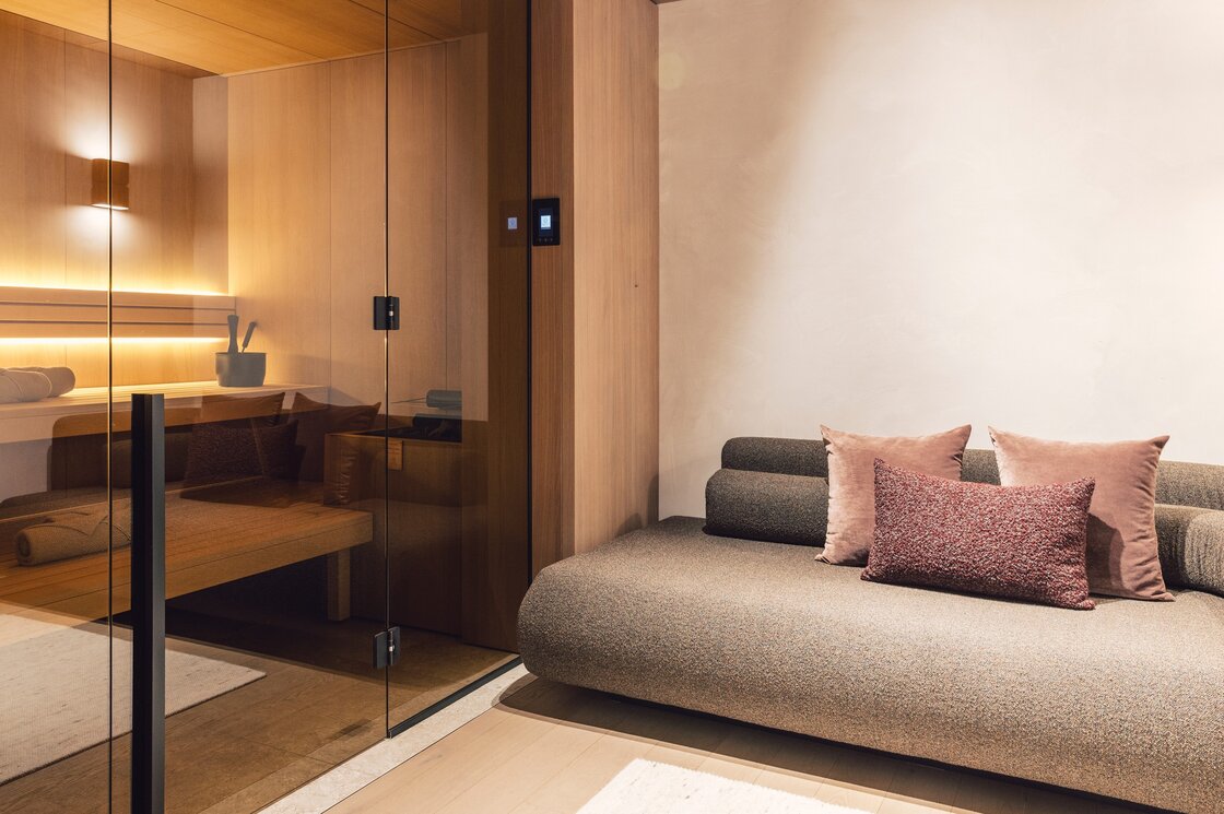 Private Sauna im Apartment in Fiss Eine private Sauna neben einer gemütlichen Sitzbank im Apartment mit warmen Holztönen.