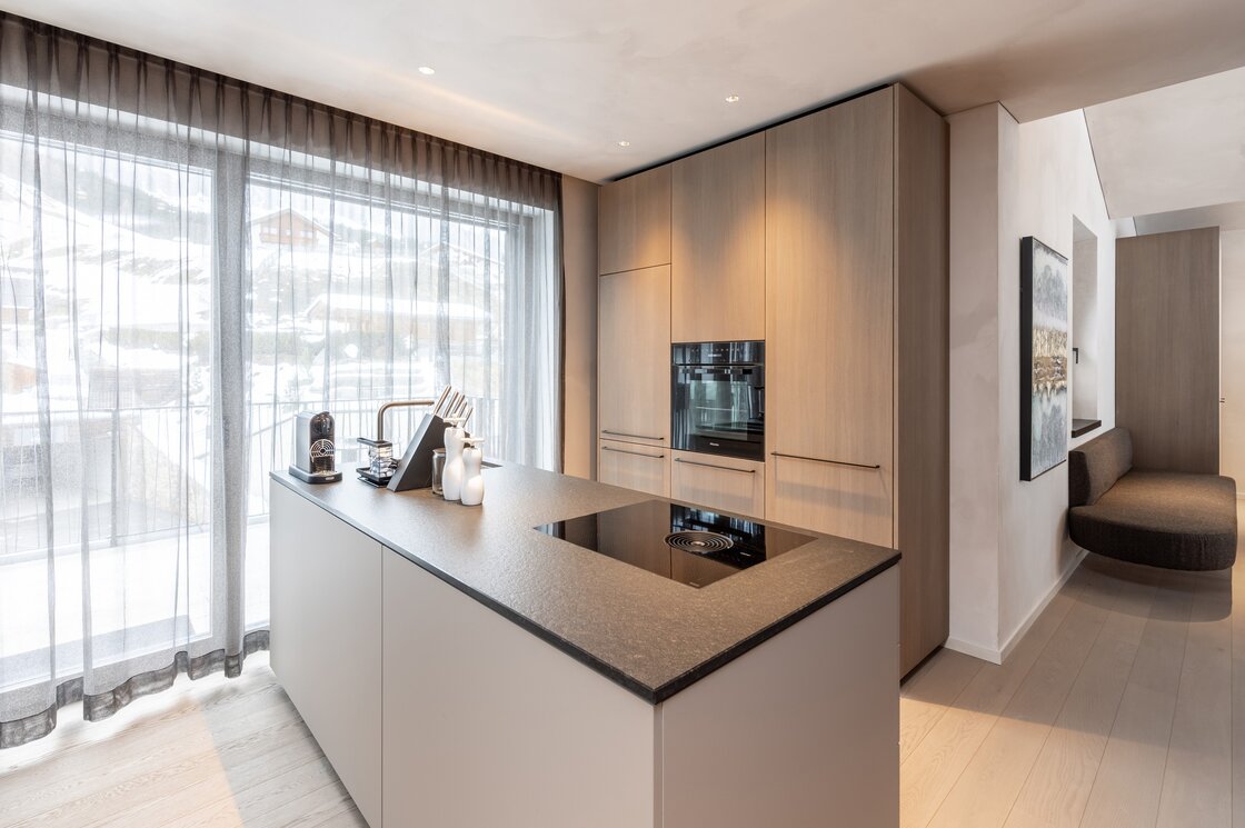 Penthouse-Küche mit Bergblick in Fiss Moderne Penthouse-Küche mit Kochinsel, großen Fenstern und Blick auf die verschneiten Berge in Fiss.