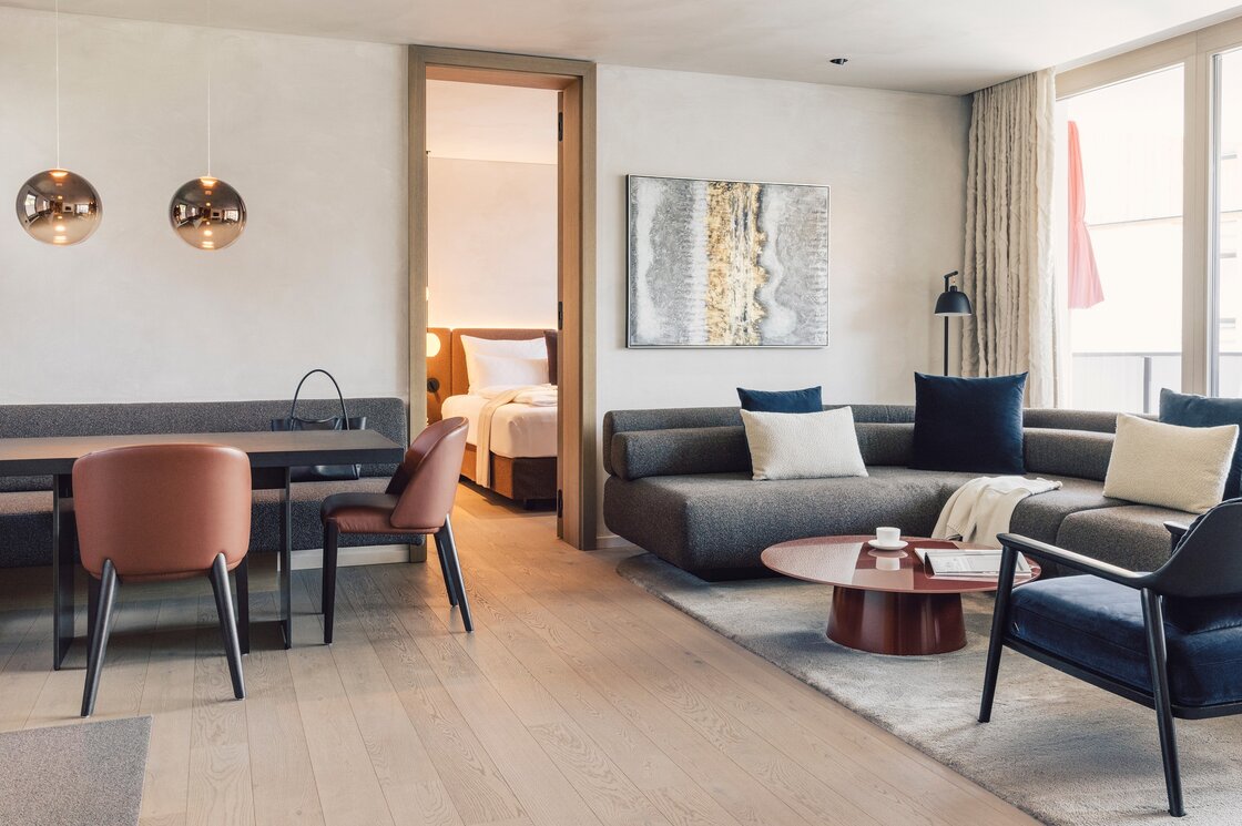 Luxury Apartment mit Wohnbereich in Fiss Heller Wohnbereich eines Luxury Apartment mit Sofa, Esstisch und offenem Durchgang zum Schlafzimmer.