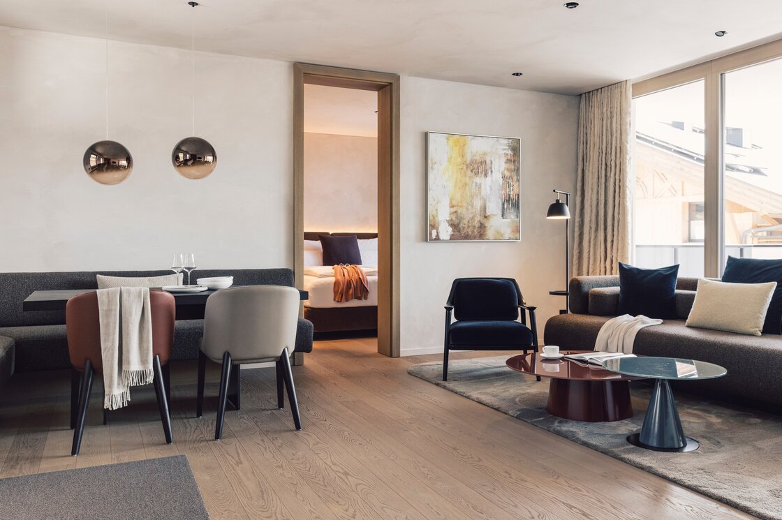 Luxus-Apartment mit Wohnbereich in Fiss Der offene Wohnbereich eines stilvollen Apartments mit Essplatz, Sofa, Sessel und Blick ins Schlafzimmer.