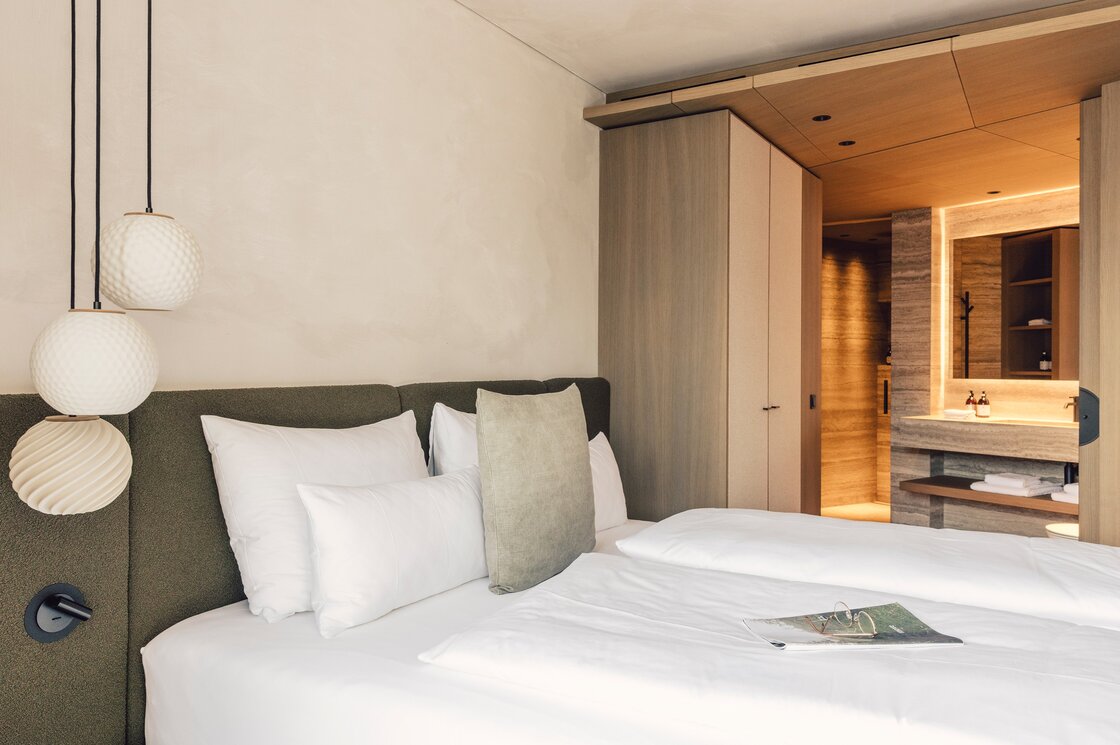 Doppelzimmer im Luxusapartment in Fiss Ein modernes Doppelzimmer mit Doppelbett, weichem Kopfteil und integriertem Badbereich.