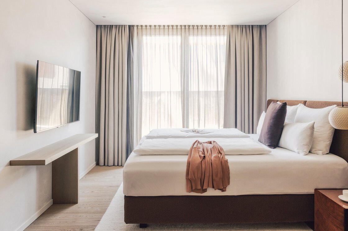 Schlafzimmer im Luxury Apartment in Fiss Ein helles Schlafzimmer mit Doppelbett, TV und bodentiefem Fenster mit Vorhängen.