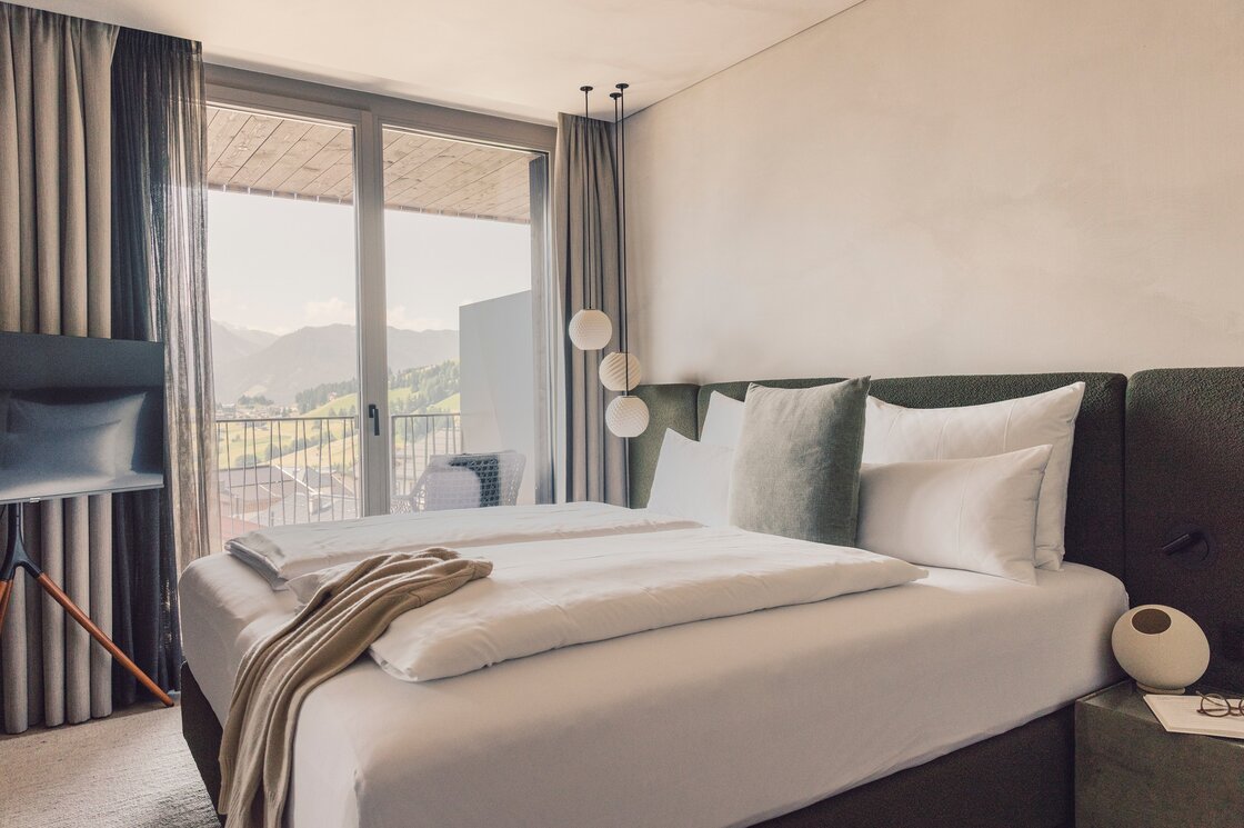 Schlafzimmer mit Bergblick im Penthouse in Fiss Ein Schlafzimmer mit Doppelbett und Blick auf die Berge durch große Glasfenster.