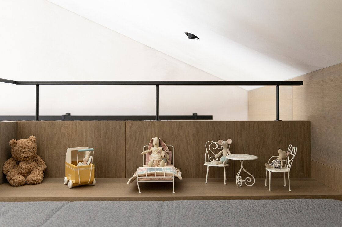 Kinderspielecke im Penthouse mit Holzdesign Eine Kinderspielecke mit Stofftieren und kleinen Möbeln unter einer Dachschräge.