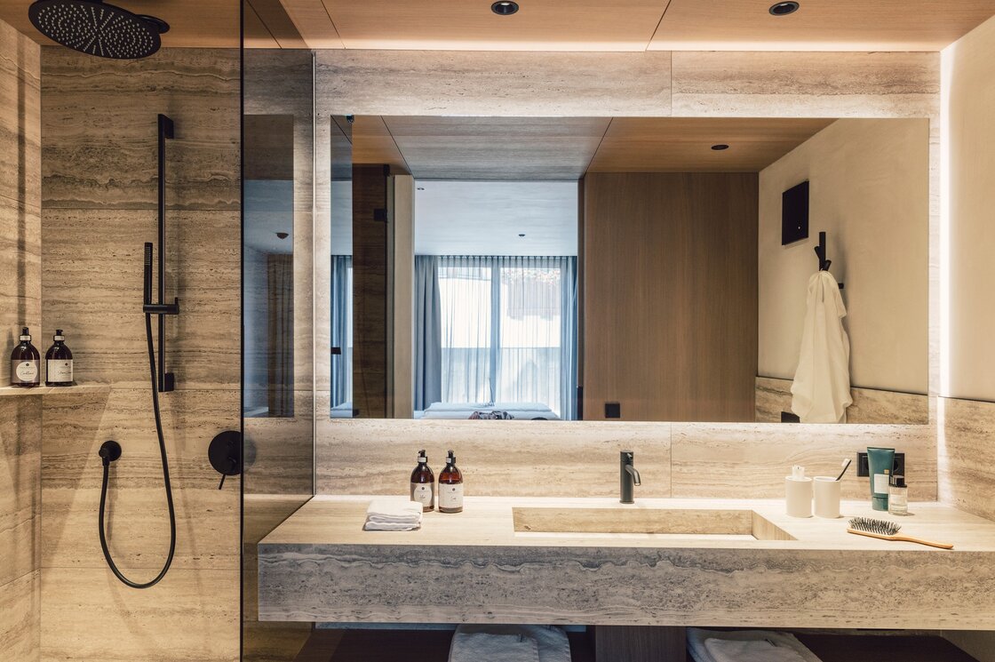 Badezimmer mit Regendusche im Luxusapartment Fiss Modernes Badezimmer mit Regendusche, großem Spiegel und Steinoptik im Apartment in Fiss.