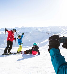 Skifahren in Serfaus-Fiss-Ladis mit Bergpanorama Skifahrer und eine snowboardende Person posieren auf einer verschneiten Piste vor den Bergen.